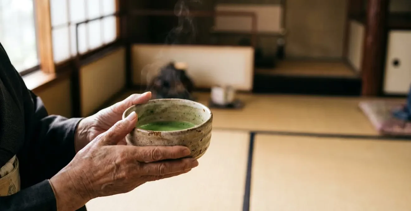 Mains tenant avec respect un bol de thé matcha fumant lors d'une cérémonie japonaise traditionnelle