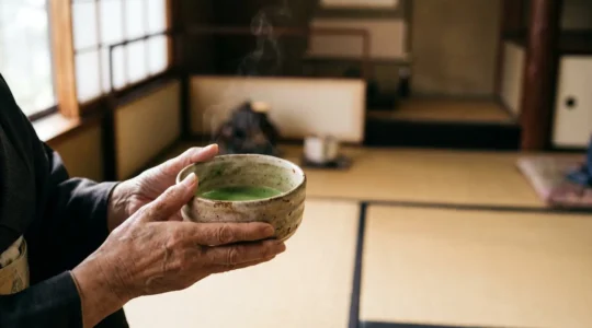 Mains tenant avec respect un bol de thé matcha fumant lors d'une cérémonie japonaise traditionnelle