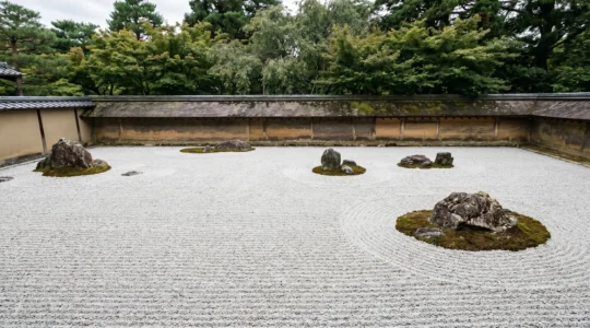 Jardin zen japonais avec gravier blanc ratissé en motifs ondulants autour de rochers, illustrant la philosophie de contemplation