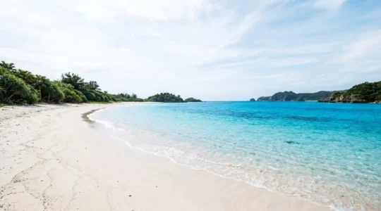 Plage paradisiaque d'Okinawa avec sable blanc et eau turquoise éclatante sous ciel bleu