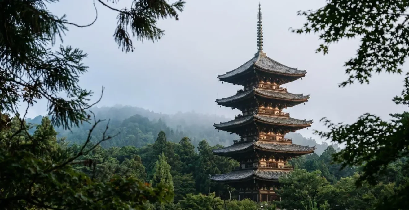 Pagode japonaise à cinq étages en bois s'élevant au-dessus de la forêt contre un ciel brumeux
