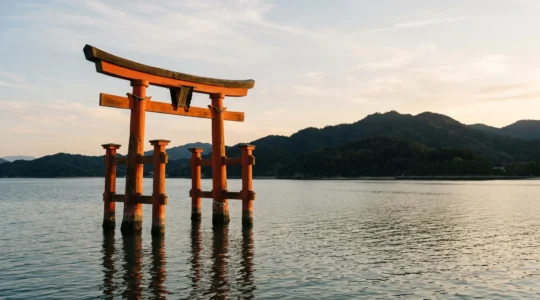 Le grand torii vermillon d'Itsukushima se reflétant dans les eaux calmes de la mer intérieure de Seto à marée haute